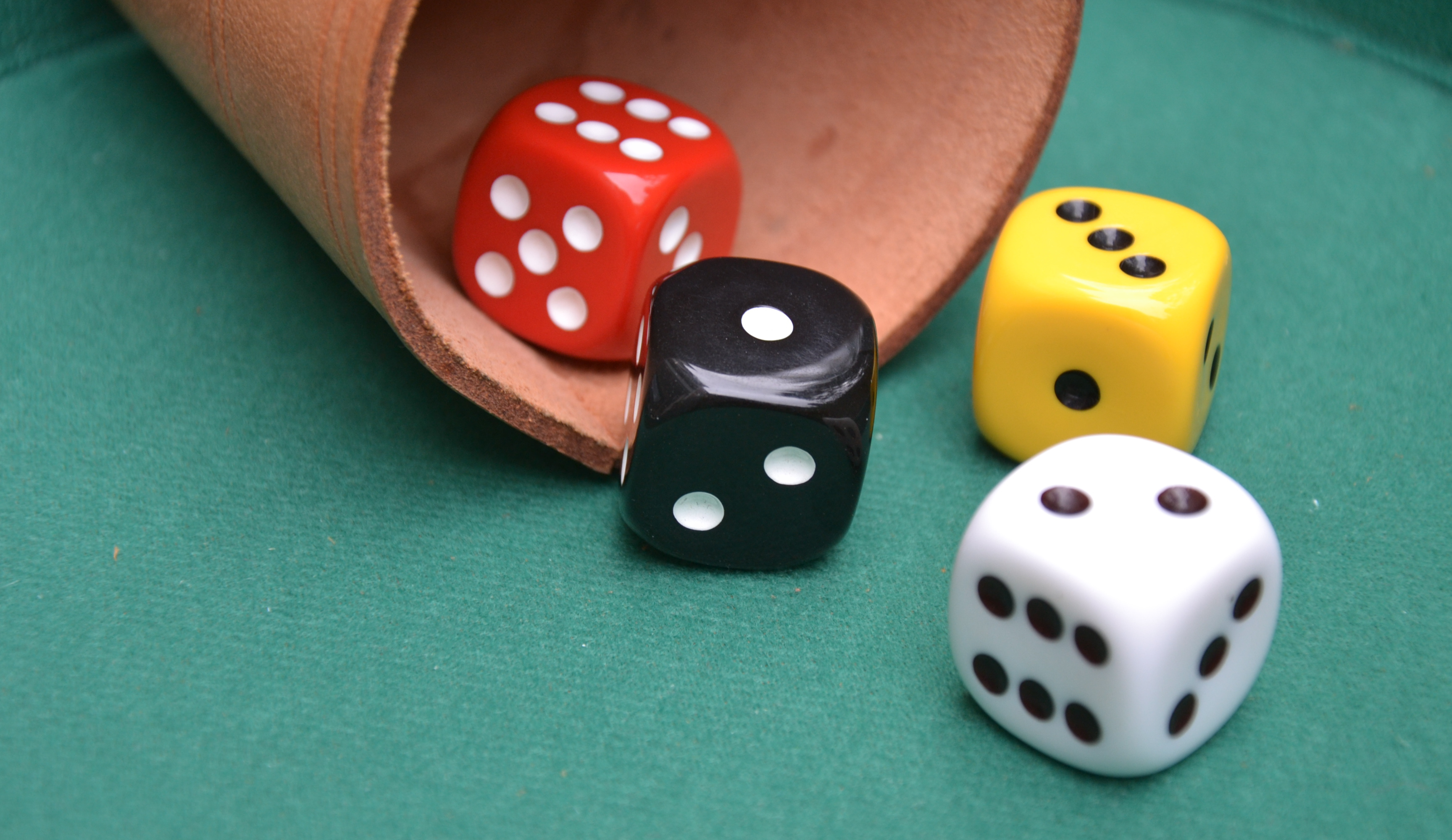 Bild vom Würfeln und einem Würfelbecher.